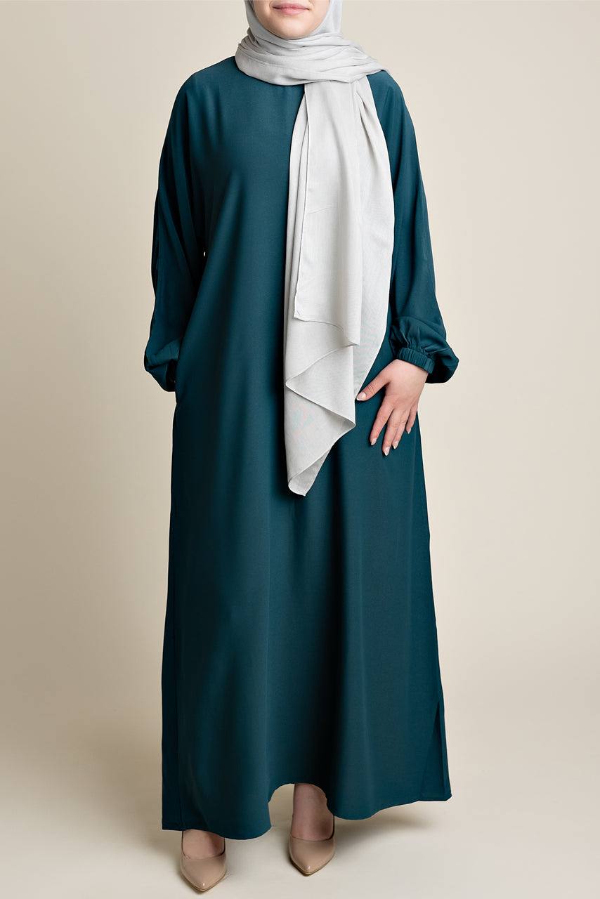 Model wearing a classic Abaya with side pockets in a dark green or teal color - Front pose - Momina Hijabs