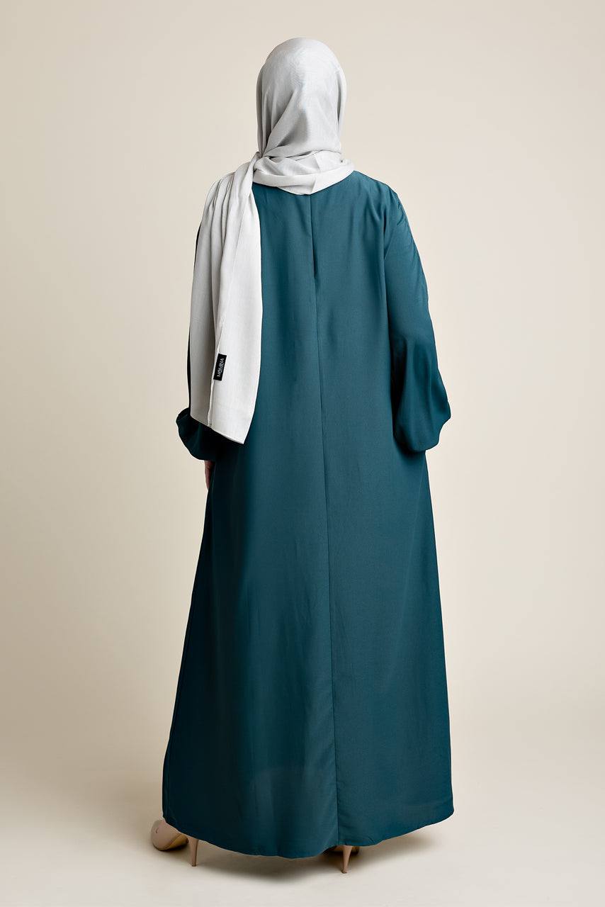 Model wearing a classic Abaya with side pockets in a dark green or teal color - Rear pose - Momina Hijabs
