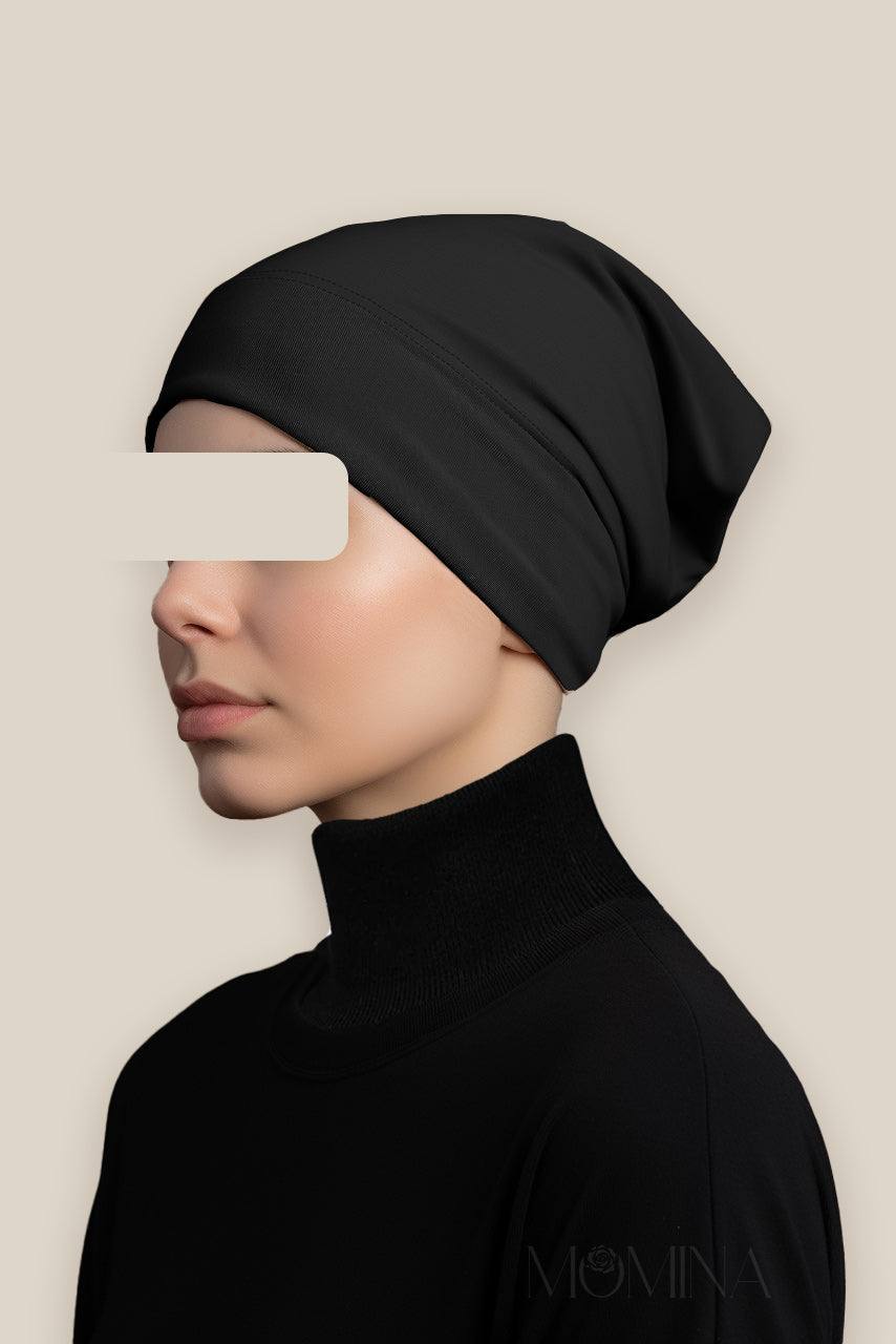 A woman wearing a black hijab tube under cap by Momina Hijabs.